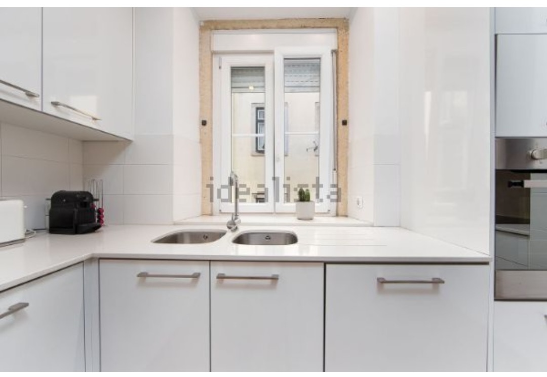 Compact white kitchen with double sink, oven and a window over the counter