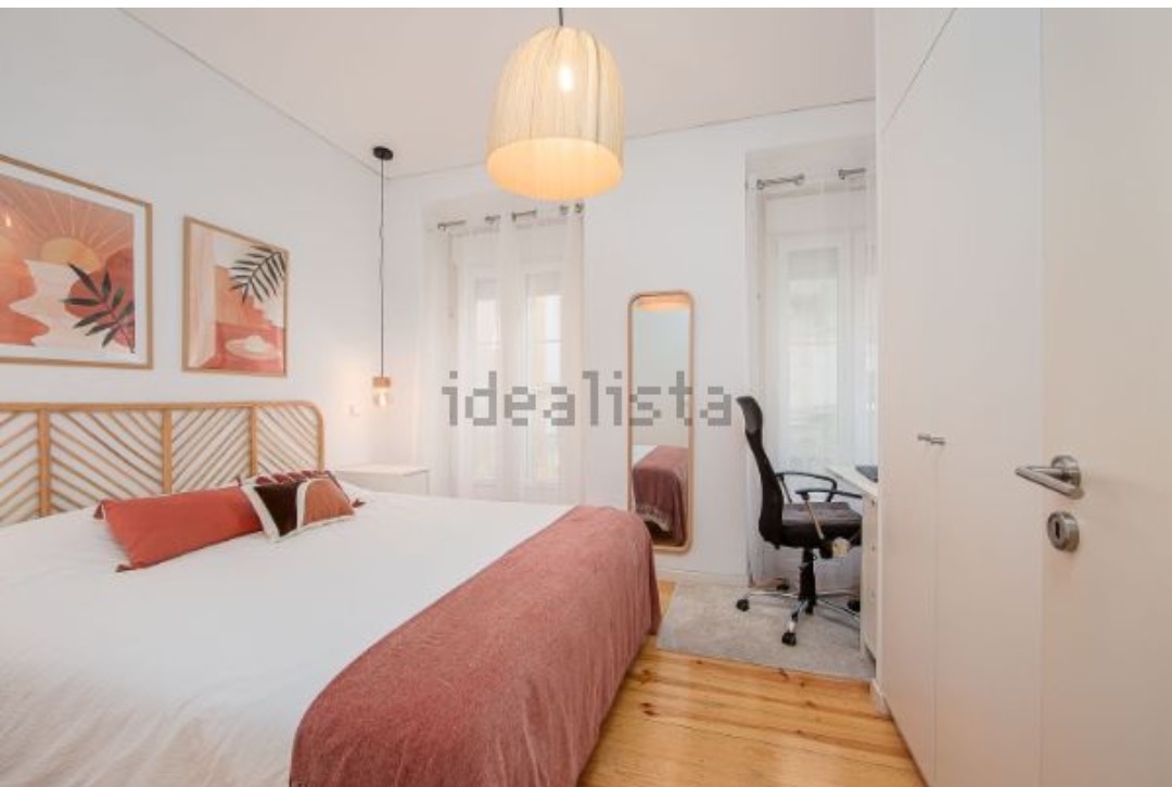 Bedroom with a rattan headboard, terracotta throw and a desk nook by the window